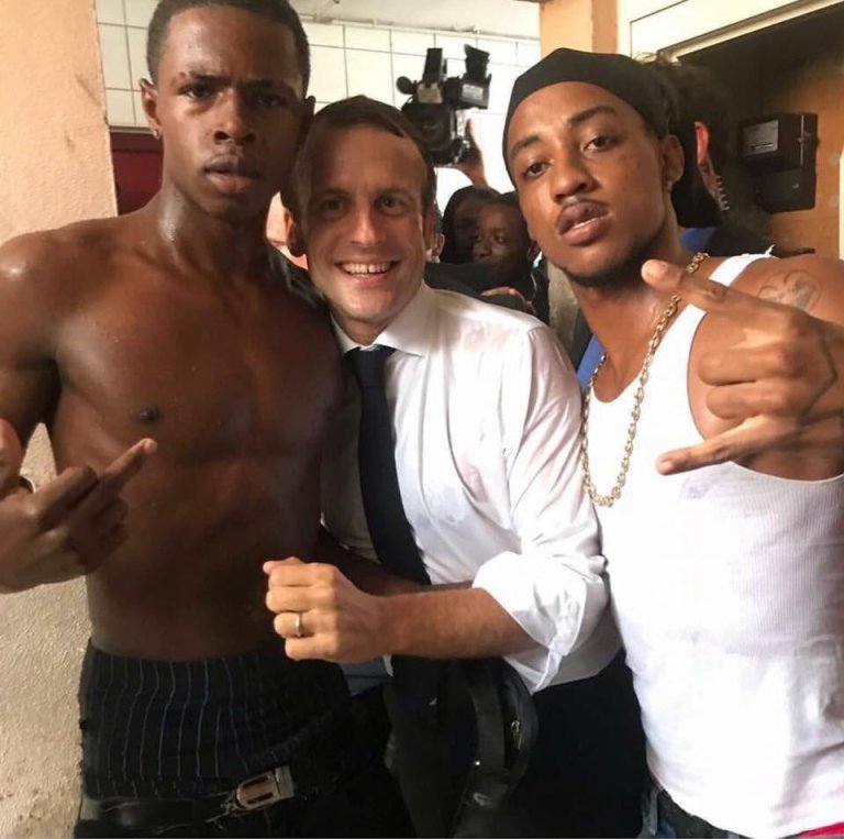 Macron smiles as he embraces half naked black buck